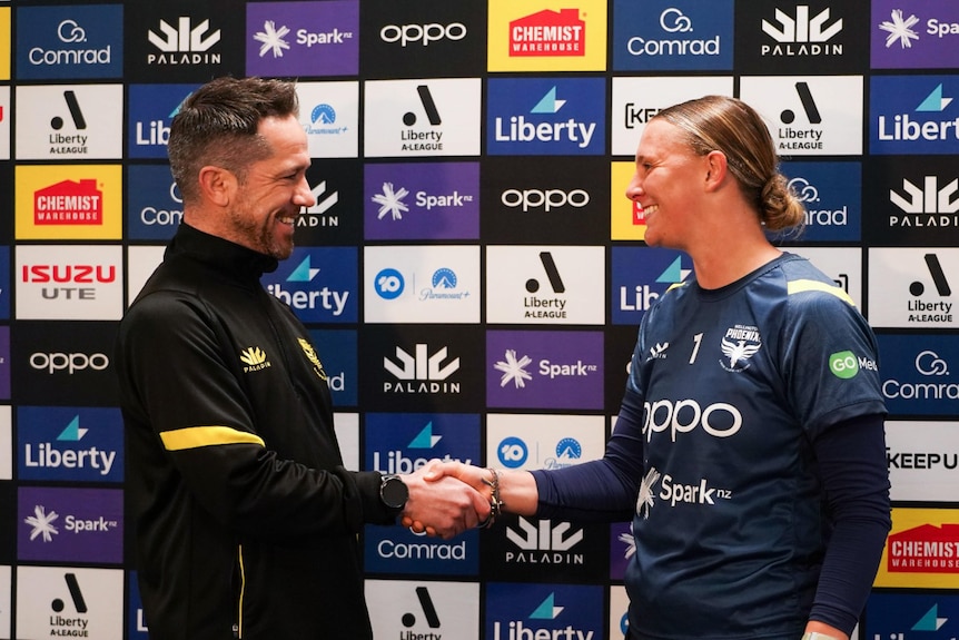 A man and woman shake hands at a sports press conference, announcing the woman has signed for the team