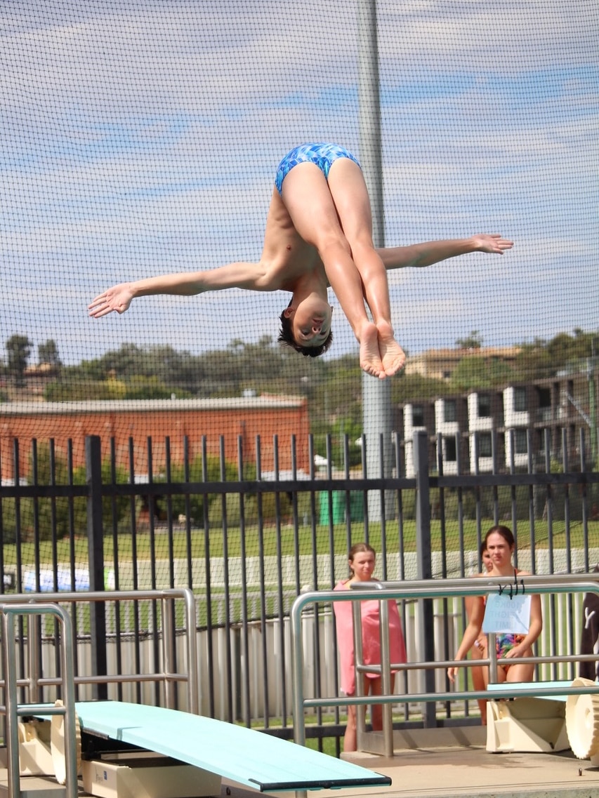 A boy with his arms out and legs together mid-air